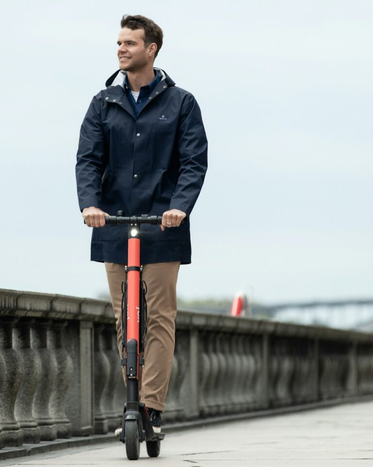 man in blue jacket and orange pants standing on bicycle during daytime